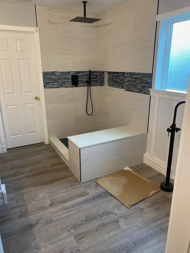 Walk-in shower with built-in bench, white wall tile and a band of blue glass mosaic