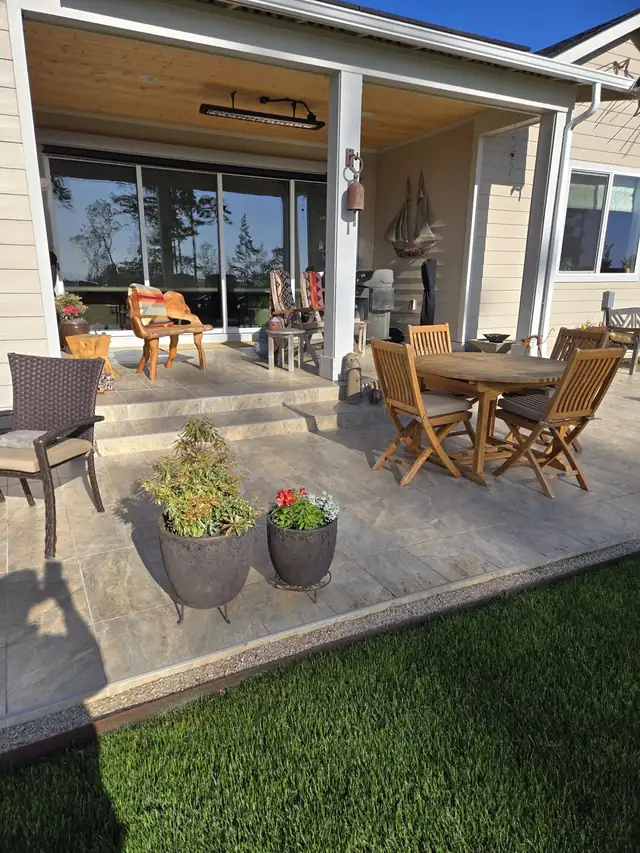 Covered back patio and steps finished in large stone-look tile with teak dining set