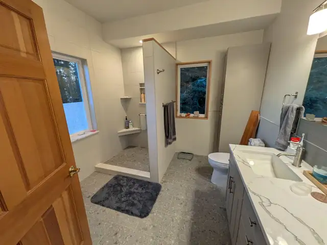 Remodeled Kala Point bathroom with tiled walk-in shower, half wall, corner bench and terrazzo-look floor tile